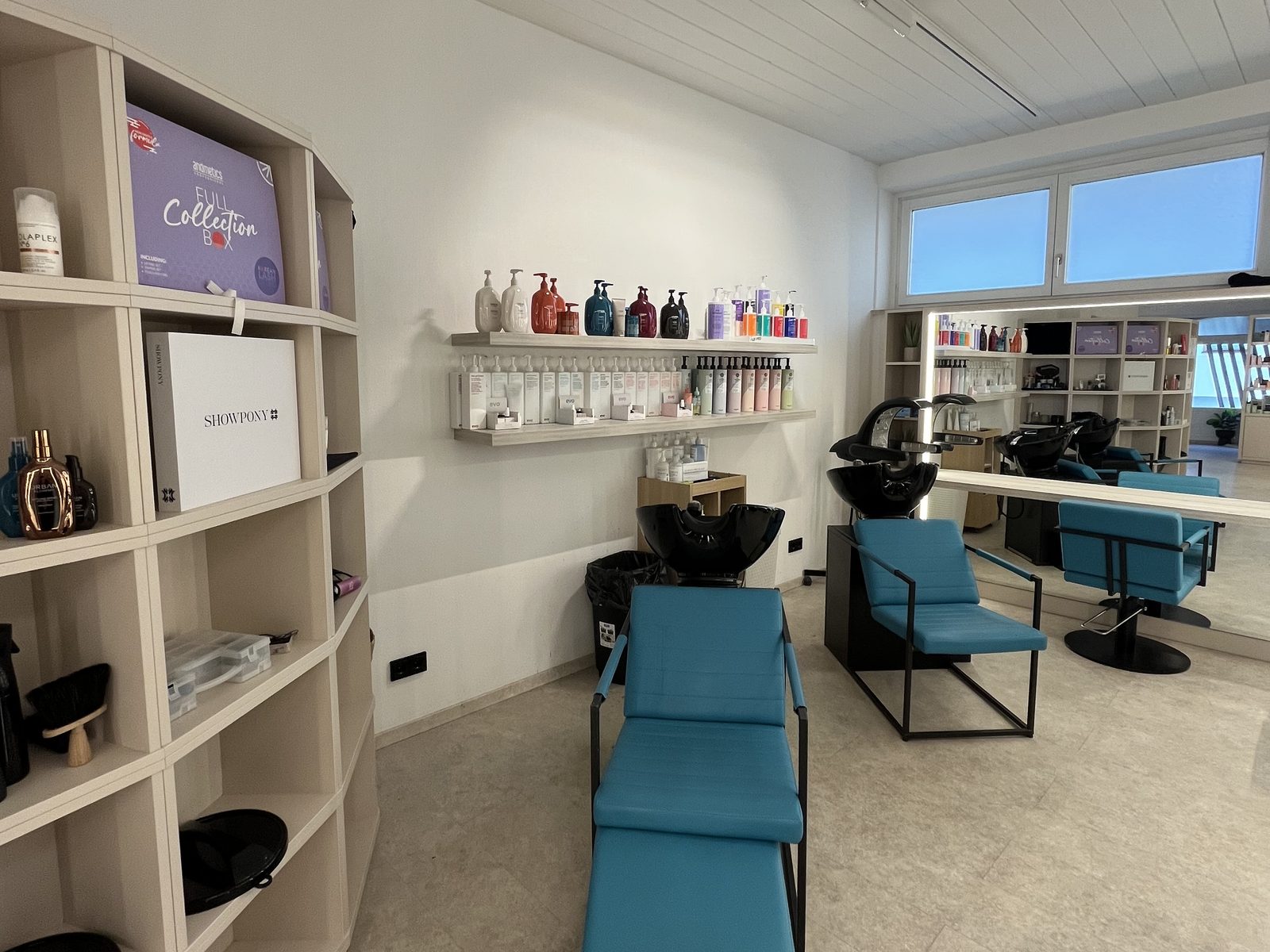 Waschbereich im HAIRLODGE Ellmau mit bequemen Waschliegen und Regalen voller Shampoos und Pflegeprodukte.
