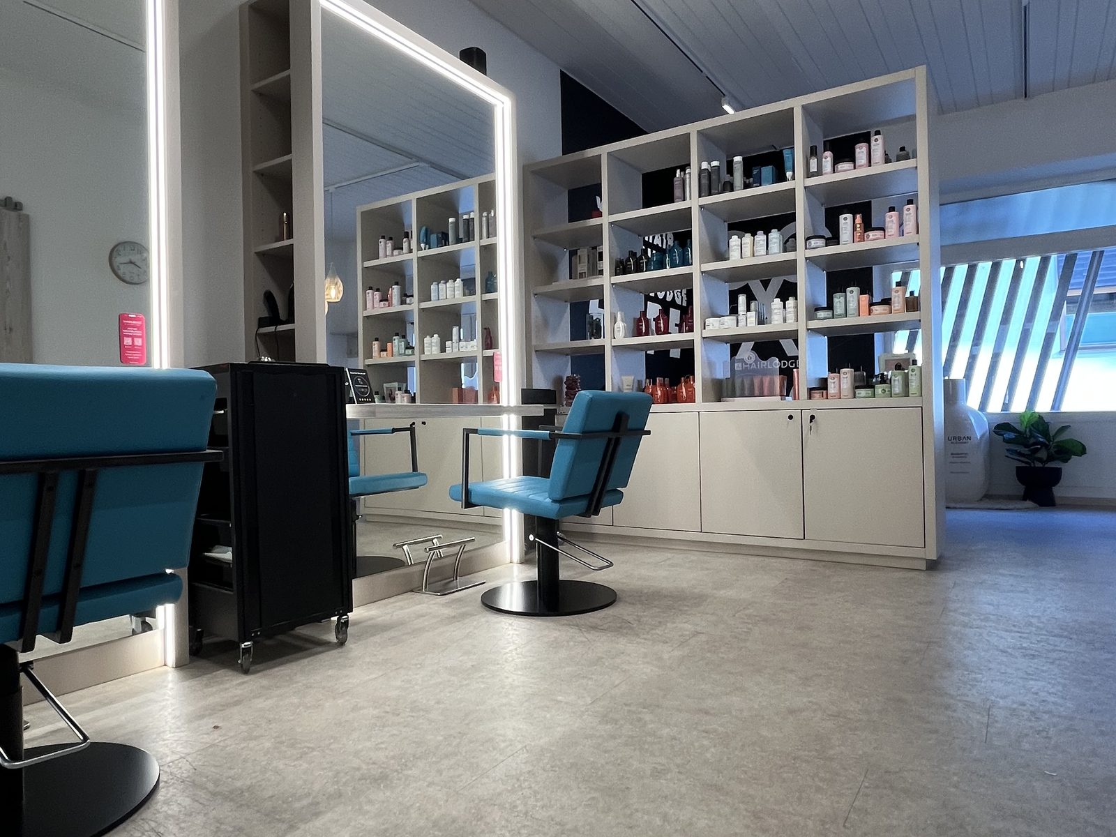 Stylingbereich im HAIRLODGE Ellmau mit Spiegelplätzen und der Regalwand mit HAIRLODGE-Branding im Hintergrund.