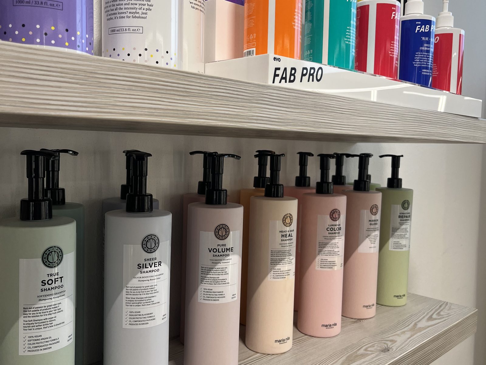 Pflegeprodukte von Maria Nila und evo im Regal des HAIRLODGE Ellmau.