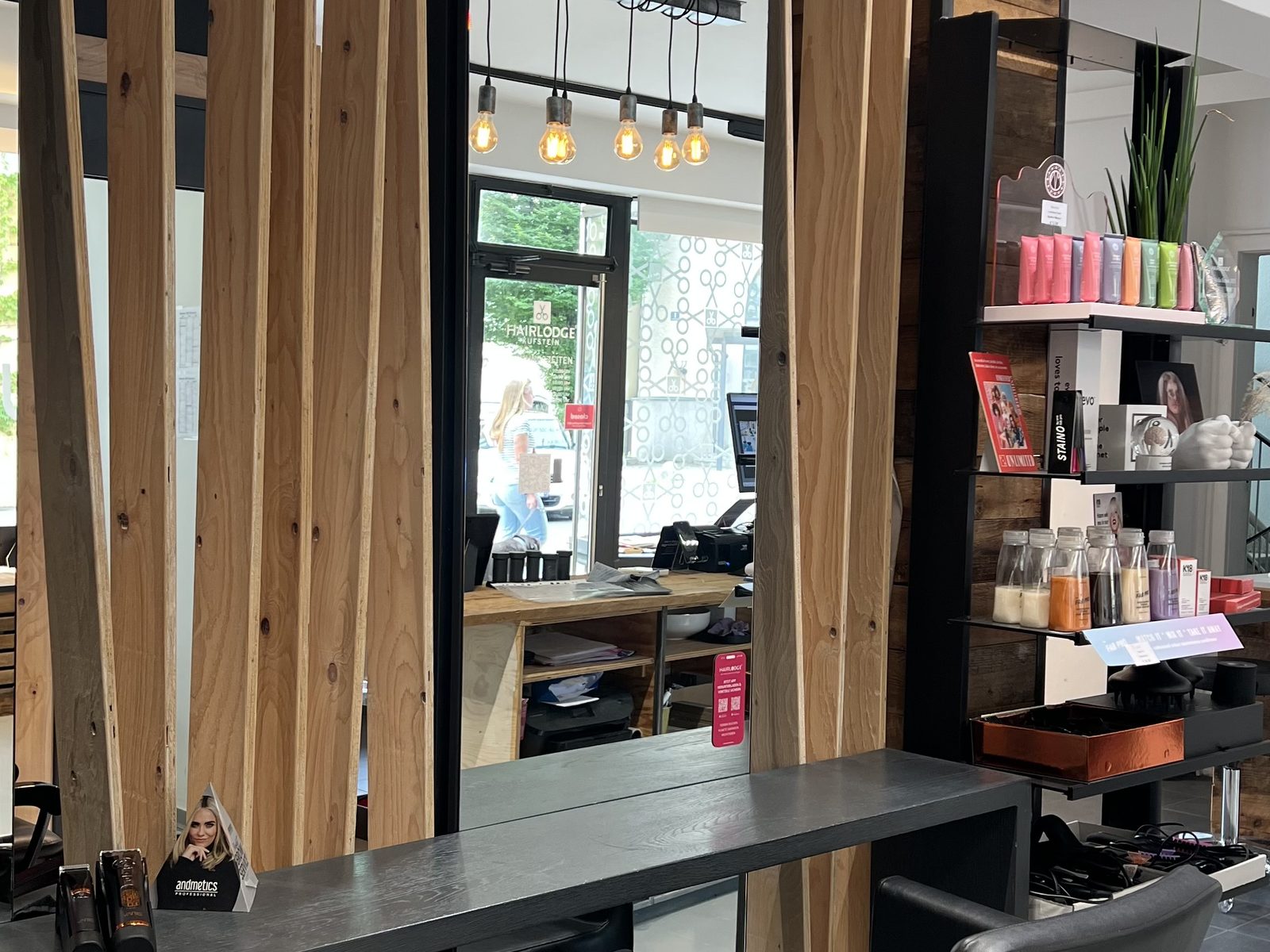 Stylingplatz im HAIRLODGE Kufstein hinter einer Holzlattenwand, mit Spiegel und Pendelleuchten.