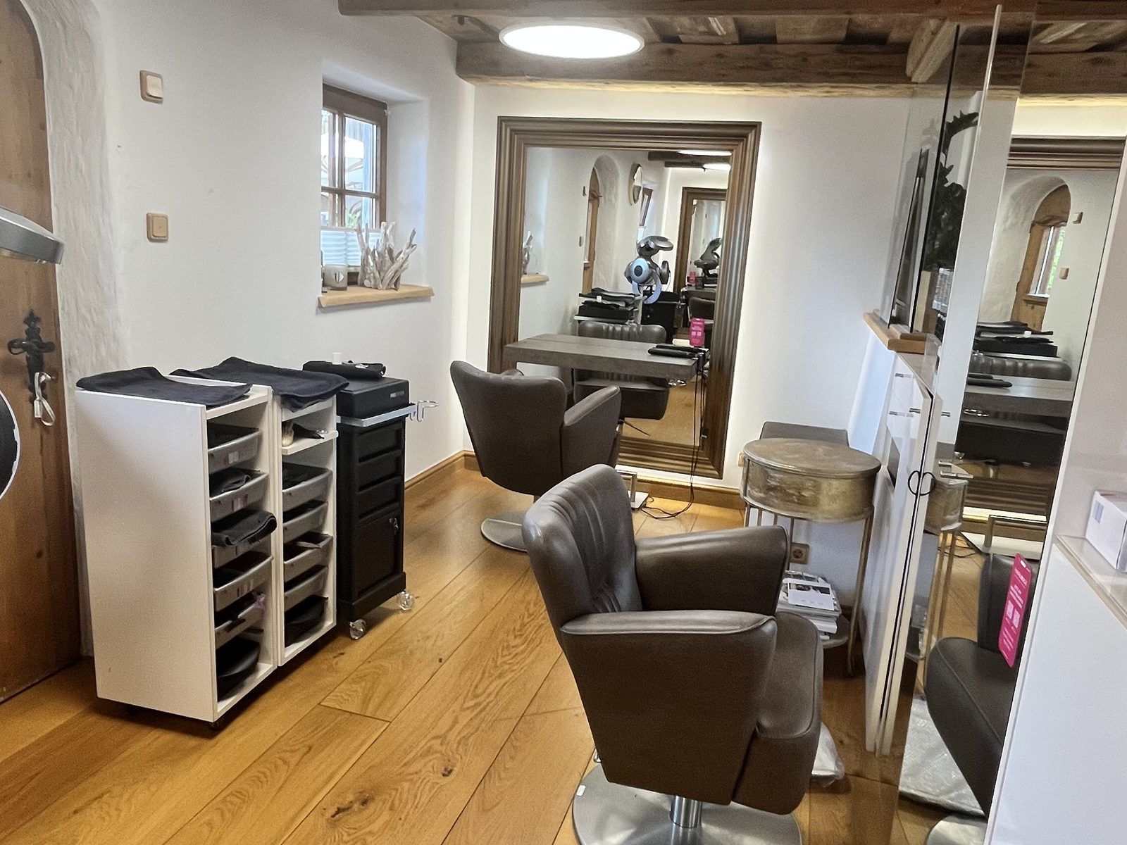 Salonraum im HAIRLODGE Stanglwirt unter der alten Holzbalkendecke, mit Stylingsesseln und Arbeitswagen.